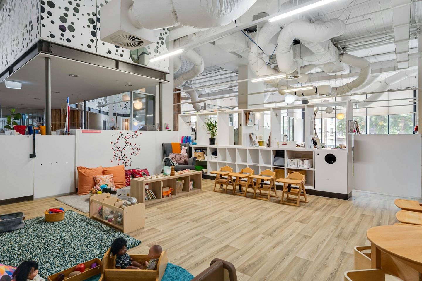 Moderner Kindergarten mit organisierten Spielecken und Holzmöbeln.