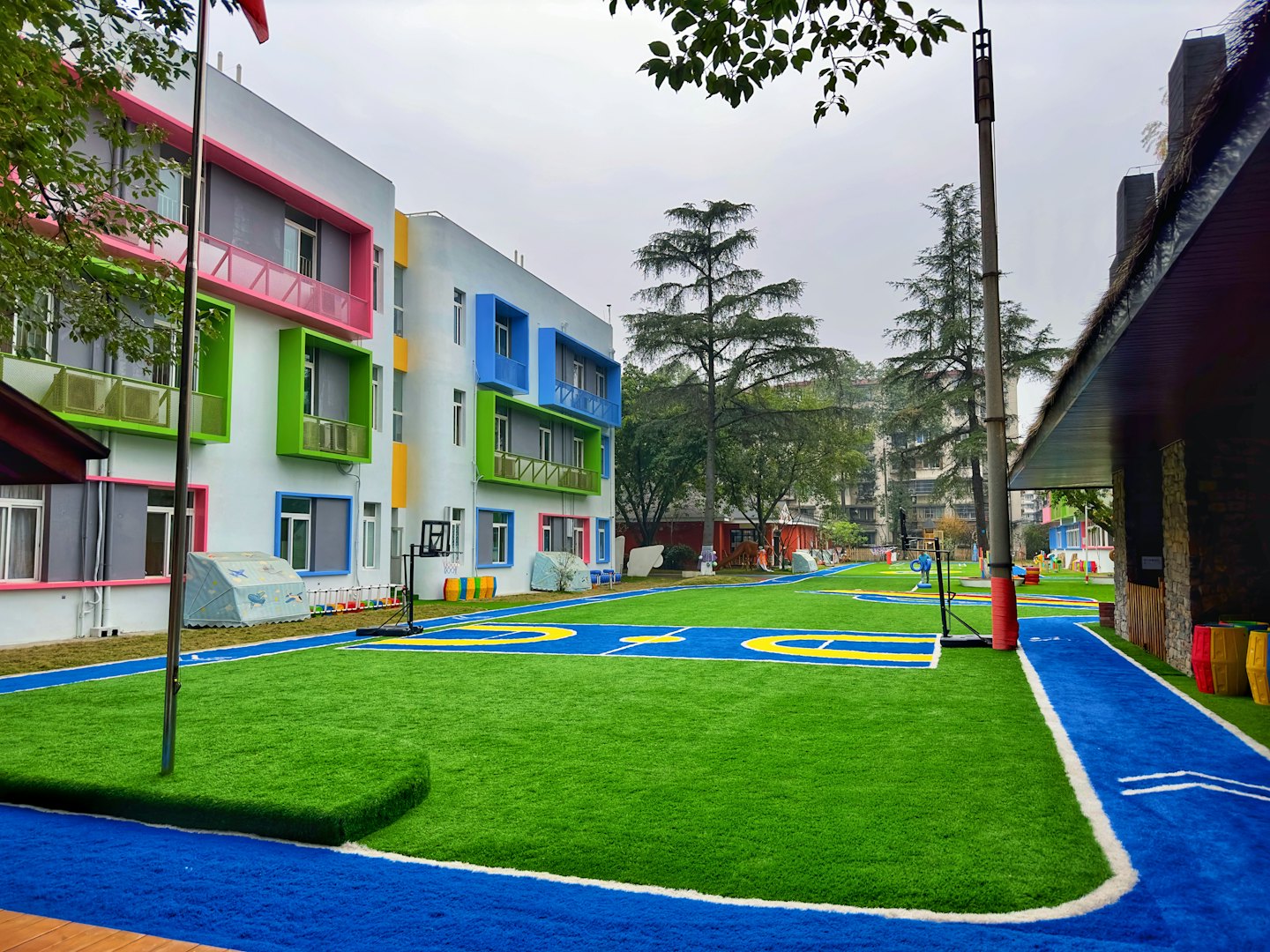 Moderner Schulbau mit buntem Spielplatz und Basketballkorb.