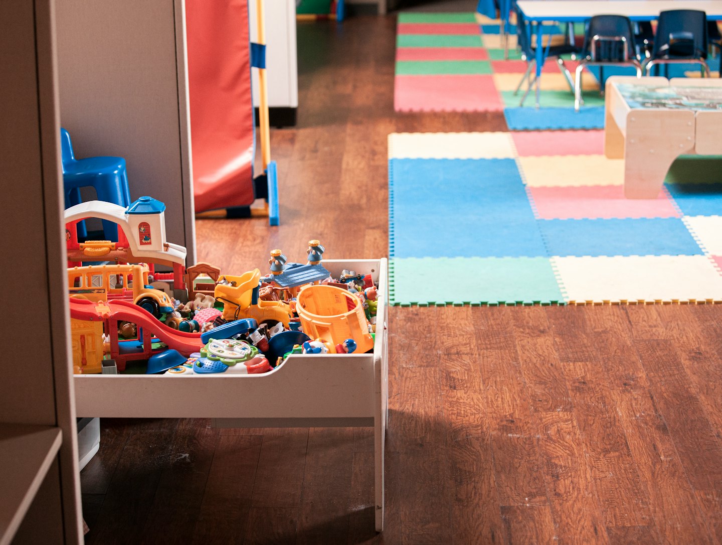 Spielzeugkiste voller bunter Kinderspielzeuge in einem Spielzimmer.